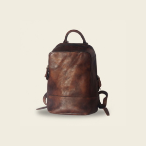 Coffee top-grain leather travel backpack, studio photograph on cream background