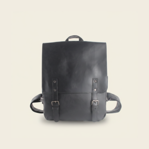 Black vegan PU leather travel laptop backpack, studio photograph on cream background