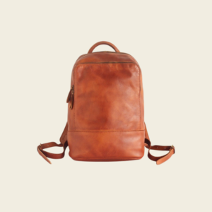Brown top-grain leather travel backpack on cream studio background